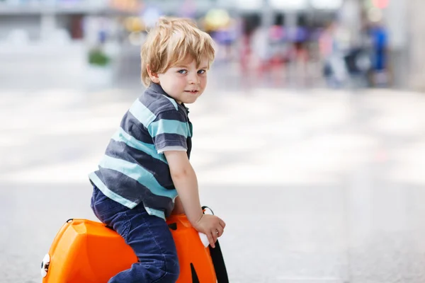 Маленький хлопчик їде у відпустку з валізою в аеропорту — стокове фото