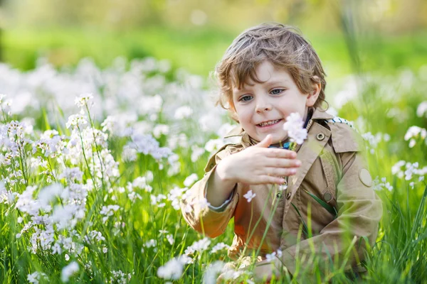 Happy little  boy in spring garden with blooming white flowers — Stock Photo, Image