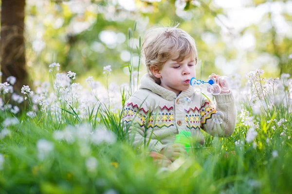 Niño feliz en el jardín de primavera con flores blancas en flor —  Fotos de Stock