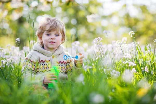 Boldog kis fiú tavaszi kert virágzó fehér virágok — Stock Fotó