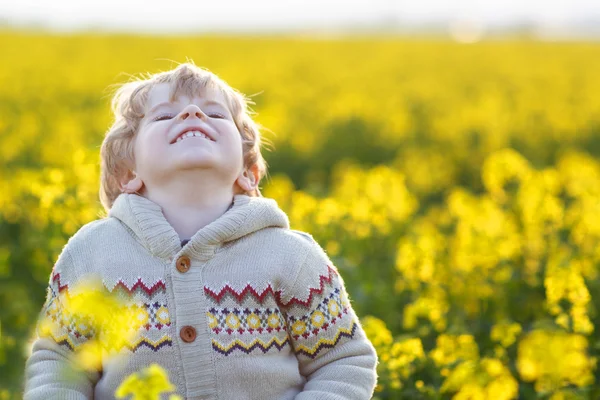 Feliz niño rubio pequeño lauging en campo de violación amarillo en un —  Fotos de Stock