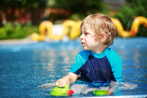 Criança bonito brincando com água na piscina exterior — Fotografia de Stock