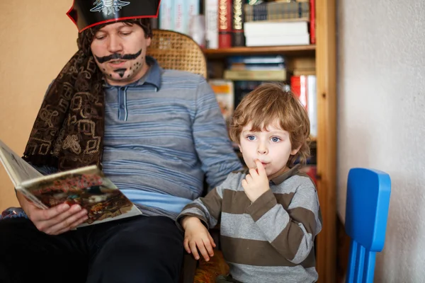 Pai lendo livro pirata para o seu filho de 4 anos, dentro de casa — Fotografia de Stock