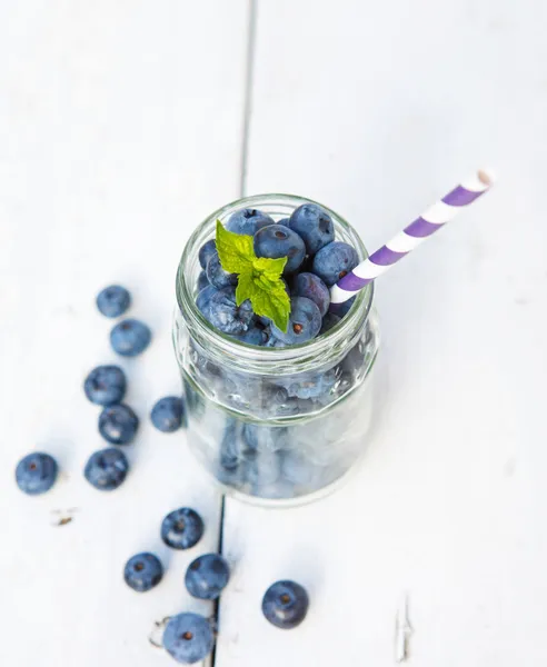 Ripe blueberries in glass jar on a wooden table — Stock Photo, Image
