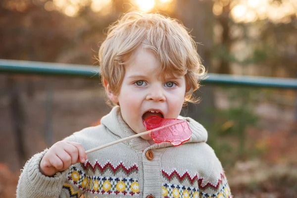 Retrato de hermoso niño de 2 años con grandes dulces, al aire libre —  Fotos de Stock