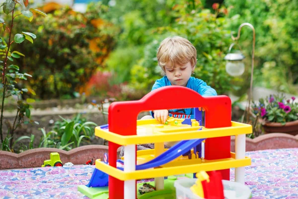 Blond toddler chłopiec gra z zabawkami - stacja parking w — Zdjęcie stockowe