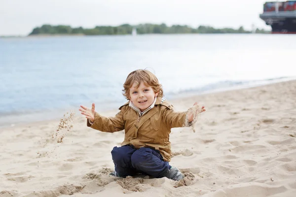 Little toddler boy playing with sand on beach of the river Elbe — Stock Photo, Image