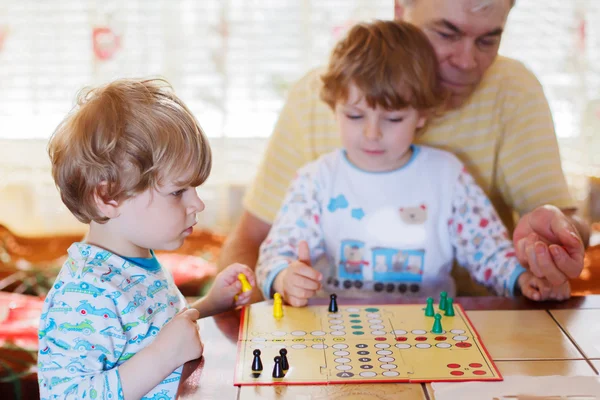 Zwei kleine Geschwister spielen mit Großvater Brettspiel — Stockfoto