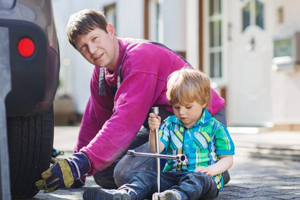 Vater und entzückender kleiner Junge reparieren Auto und wechseln Rad — Stockfoto