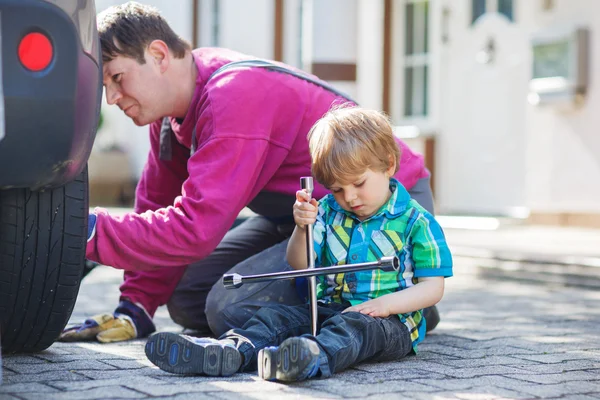 Vater und entzückender kleiner Junge reparieren Auto und wechseln Rad — Stockfoto