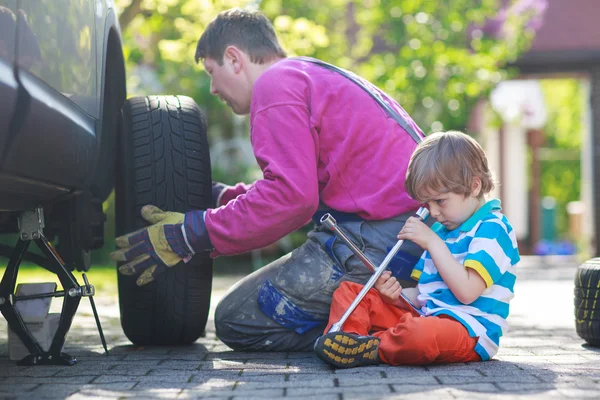 Pai e adorável menino reparando carro e mudança de roda — Fotografia de Stock