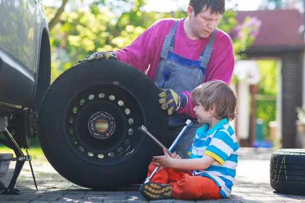 Far och bedårande liten pojke reparera bilen och byta hjul — Stockfoto