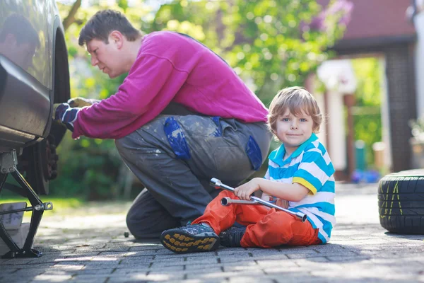 Vater und entzückender kleiner Junge reparieren Auto und wechseln Rad — Stockfoto