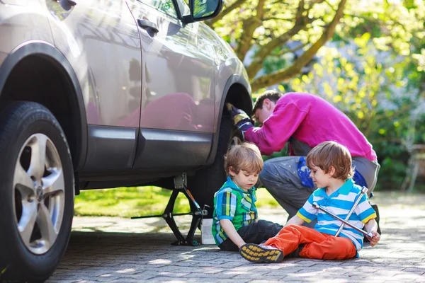 Pai e dois meninos reparando carro e trocando roda toge — Fotografia de Stock