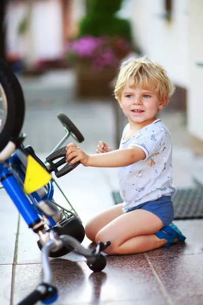 Szczęśliwego malucha zabawny chłopak dwa lata naprawy jego pierwszy rower — Zdjęcie stockowe