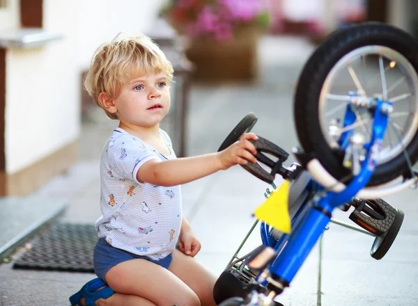 Fröhlicher lustiger Kleinkind Junge von zwei Jahren repariert sein erstes Fahrrad — Stockfoto
