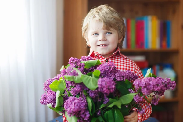 Menino sorridente adorável com flores lilás florescendo — Fotografia de Stock