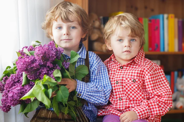 Two adorable little sibling boys with blooming lilac flowers — Stock Photo, Image