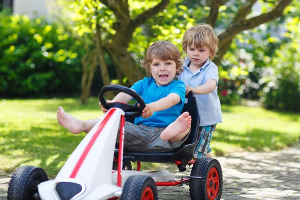 Dos hermanos felices jugando con el coche de juguete — Foto de Stock