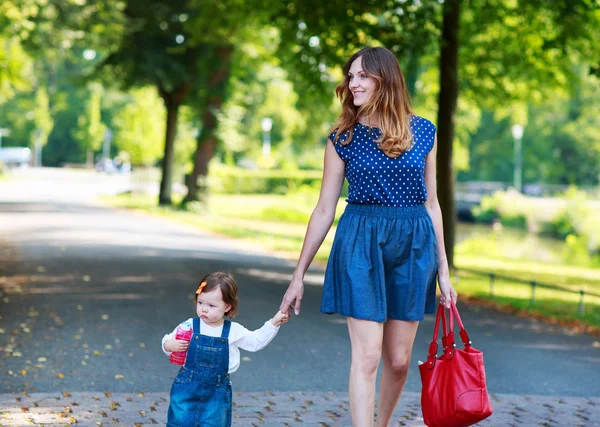 Feliz madre joven y adorable niña pequeña caminando a través de la suma —  Fotos de Stock