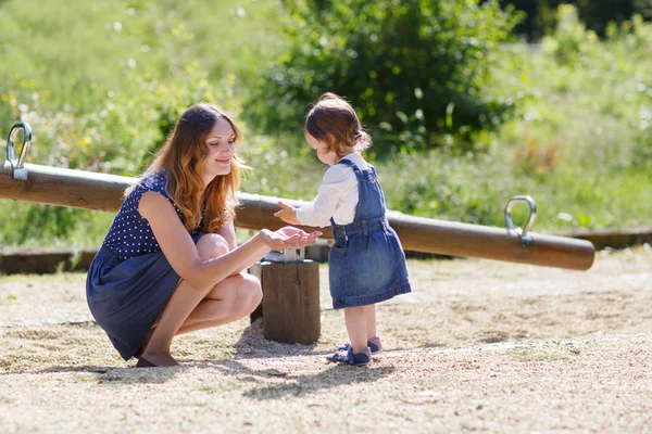 Happy young mother and adorable toddler girl walking through sum — Stock Photo, Image