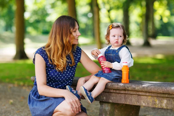 Happy young mother and adorable toddler girl walking through sum — Stock Photo, Image