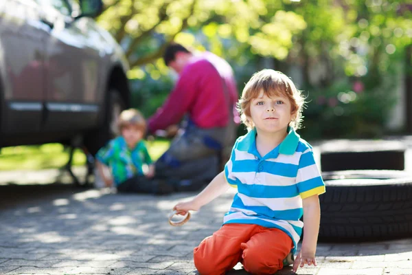 Pappa och två små pojkar reparera bilen och byta hjul toge — Stockfoto