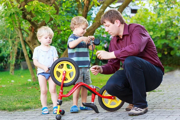 Twee kleine broer of zus jongens fietswiel met vader herstellen — Zdjęcie stockowe