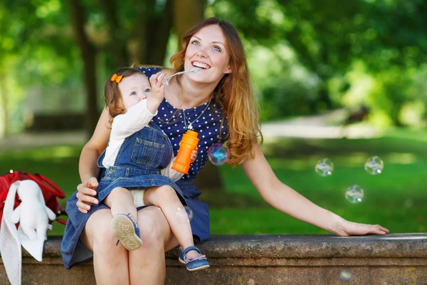 Feliz madre joven y adorable niña pequeña caminando a través de la suma — Foto de Stock