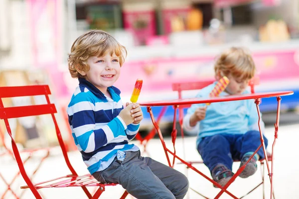 Dos niños - hermanos comiendo helado colorido en verano — Foto de Stock