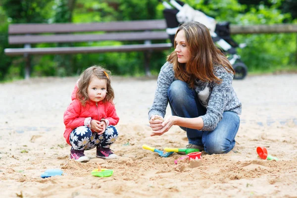 Мать и маленькая дочь играют вместе на детской площадке — стоковое фото
