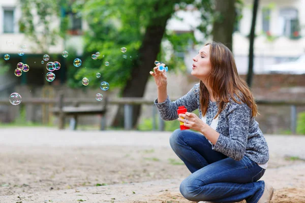 Hermosa joven jugando con burbujas de jabón en el parque — Foto de Stock
