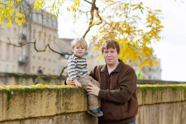 Little child and young father in autumn city — Stock Photo, Image