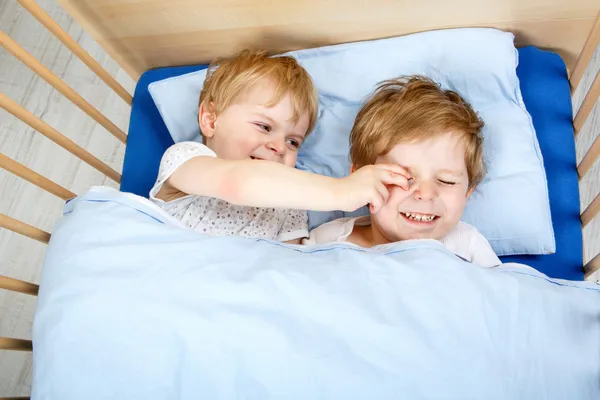 Маленькие братья и сёстры веселятся в постели дома — стоковое фото
