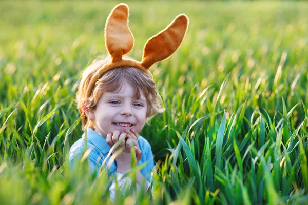 Niedliches kleines Kind mit Osterhasenohren im grünen Gras — Stockfoto