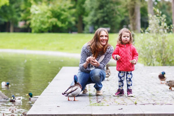 Mor och hennes dotter mata ankor på sommaren — Stockfoto