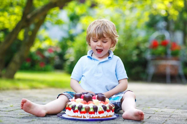 Menino comemorando seu aniversário no jardim de casa com grande ca — Fotografia de Stock