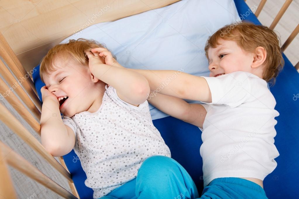 little sibling boys having fun in bed at home