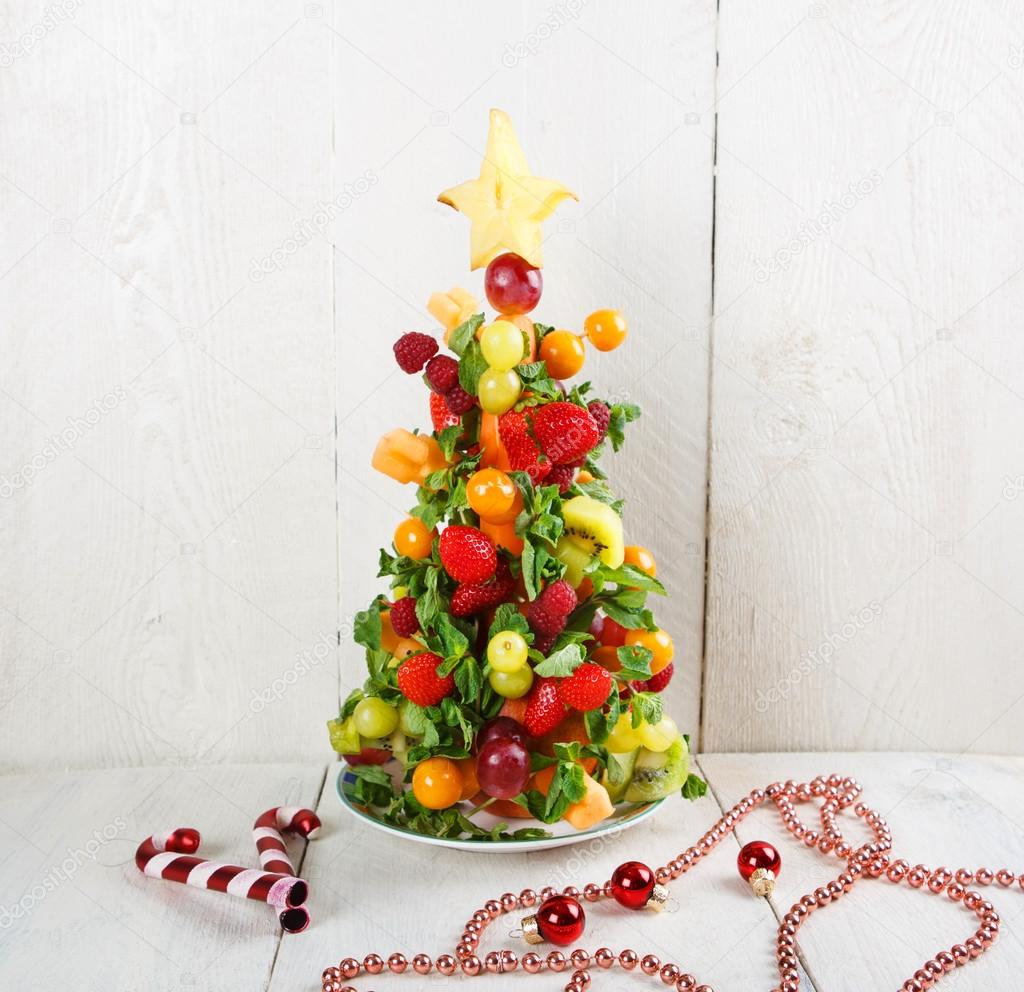 Fruit Christmas tree with different berries, fruits and mint