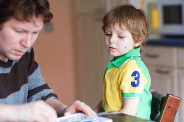 Küçük oğlunun yüzüne Brezilya bayrağı boyama baba