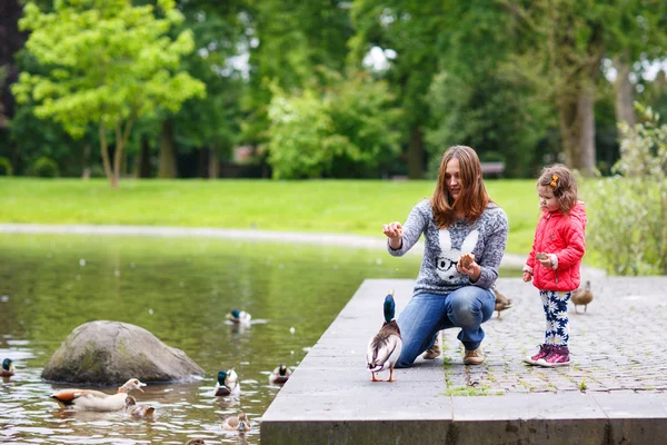 Mãe e sua filha alimentando patos no verão — Fotografia de Stock