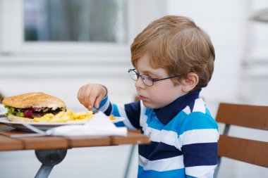 küçük çocuk hızlı yemek yeme: hamburger ve patates kızartması