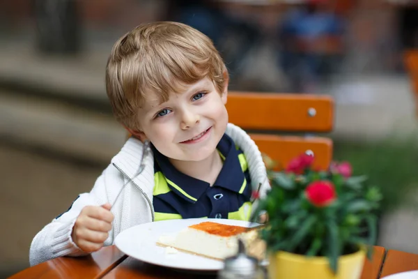 Malý chlapec jíst dort v venkovní kavárně. — Stock fotografie