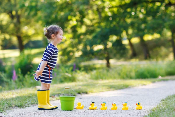 Adorable little girl with rubber ducks in summer park — Stock Photo, Image