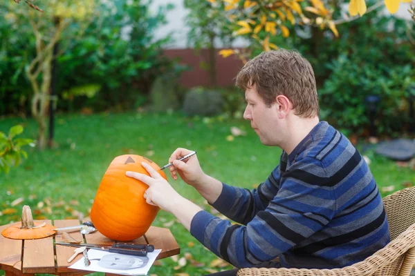 Young man making halloween pumpkin — Stock Photo, Image