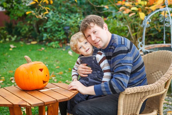 Jonge man en peuter jongen halloween pompoen maken — Stockfoto