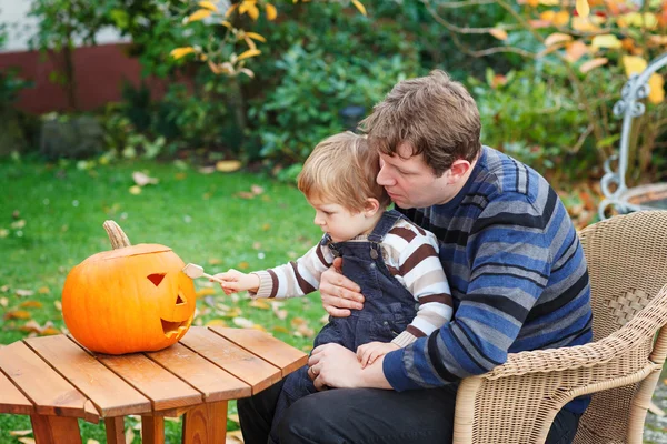 Young man and toddler boy making halloween pumpkin — Stock Photo, Image