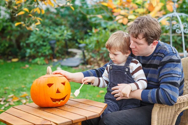 Jonge man en peuter jongen halloween pompoen maken — Stockfoto