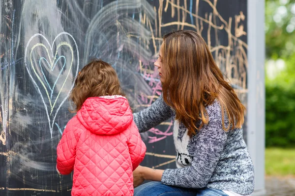 Mutlu anne ve küçük kızı parkta tebeşir ile boyama — Stok fotoğraf