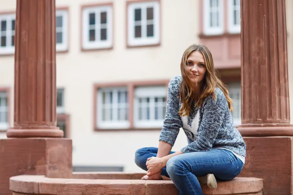 Beautiful girl sitting on fountain in german city — Stock Photo, Image